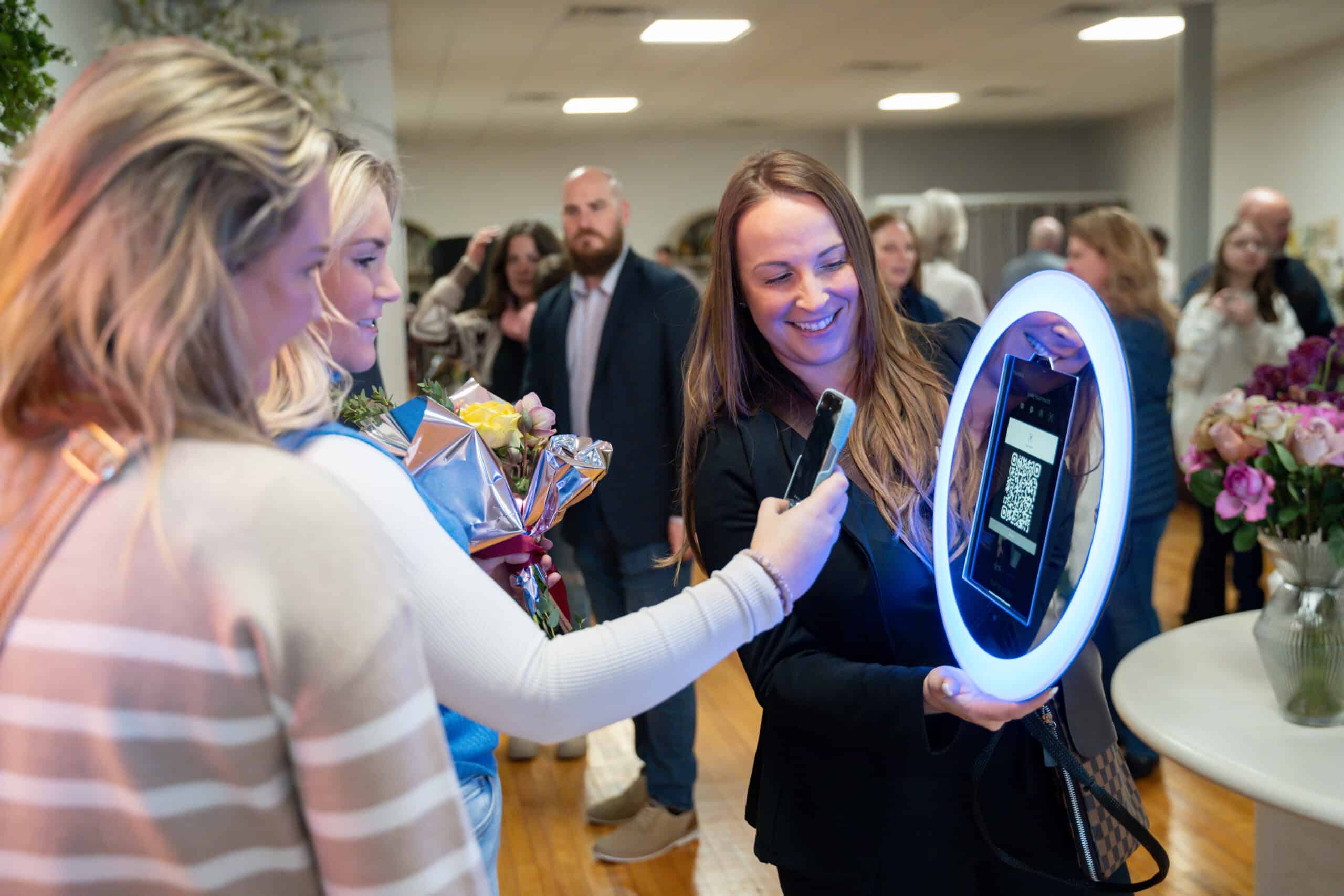 Guests gathered around a roaming photographer holding a ring light at a corporate reception