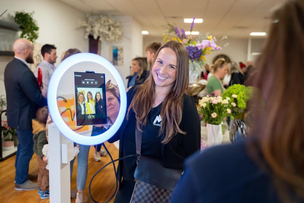 Smiling guest taking a selfie at a ring-light photo booth during a corporate brand activation event in New England