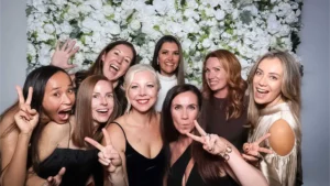 A group of people posing for a photo booth with a white floral backdrop