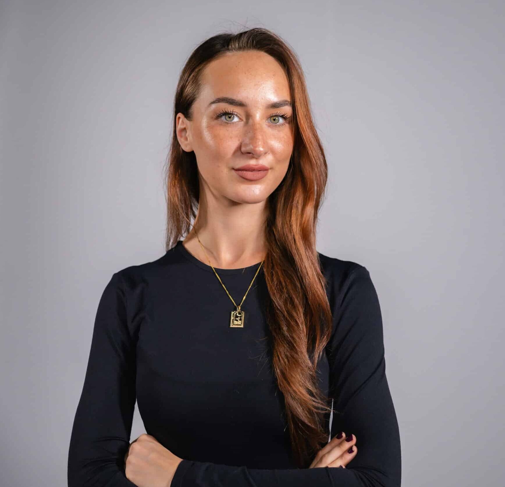 Professional headshot of a woman in a dark top on a grey studio backdrop, captured live at a corporate event