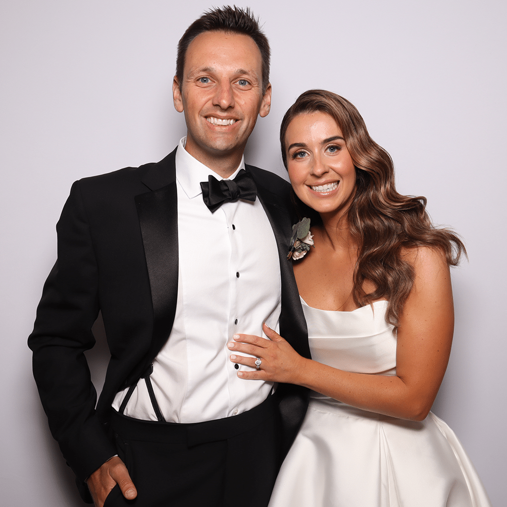 Bride and groom posing for a luxury GLAM photo booth portrait featuring soft skin smoothing, studio-quality lighting, and a clean elegant backdrop.