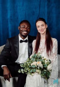 A couple posing in front of a blue backdrop