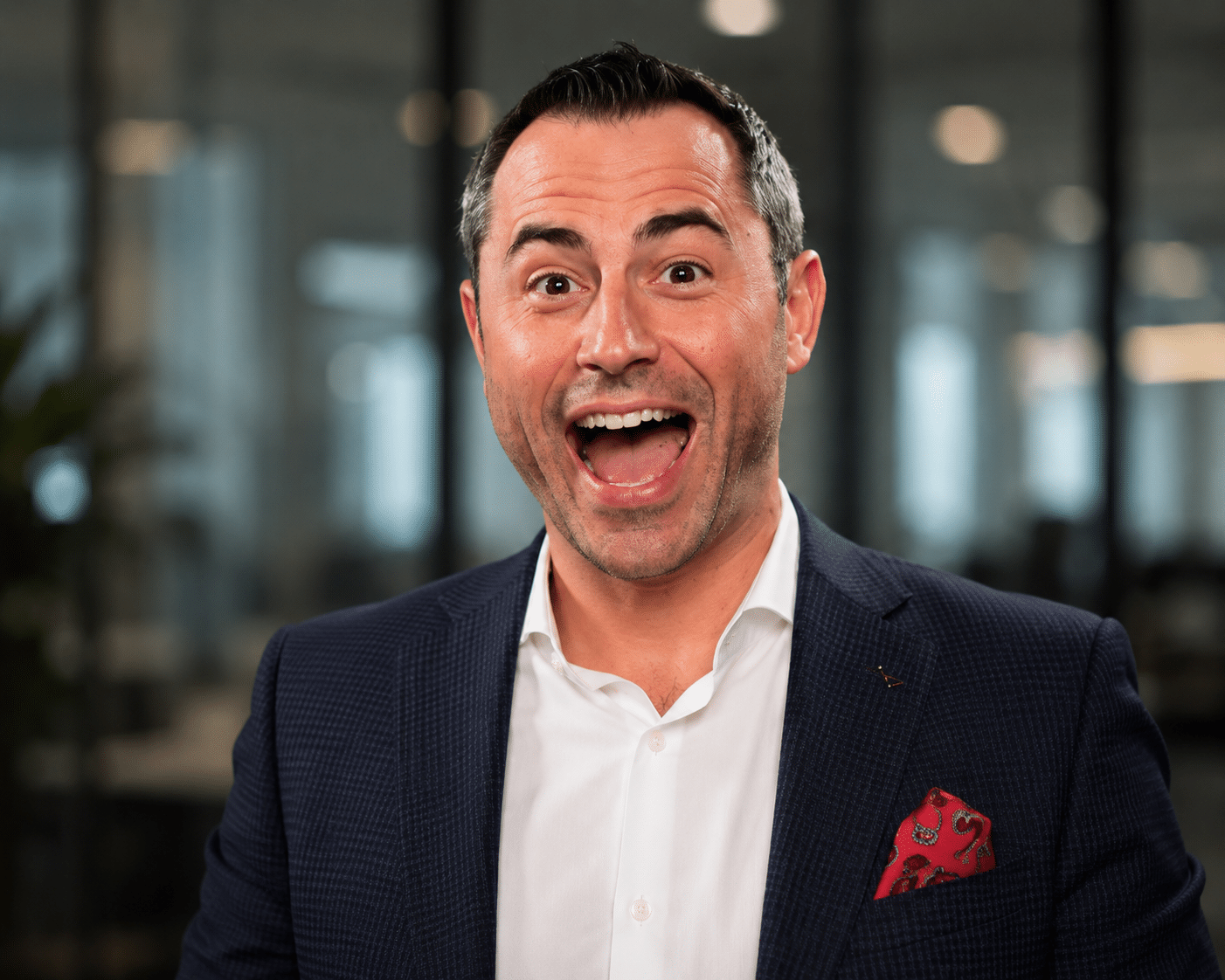 Professional man in a suit with a red pocket square, set against a modern office background, showcasing AI-enhanced headshot capabilities for events.