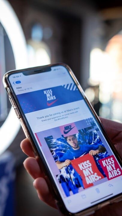 Text message showing a Nike "Kiss My Airs" branded photo booth picture on a smartphone