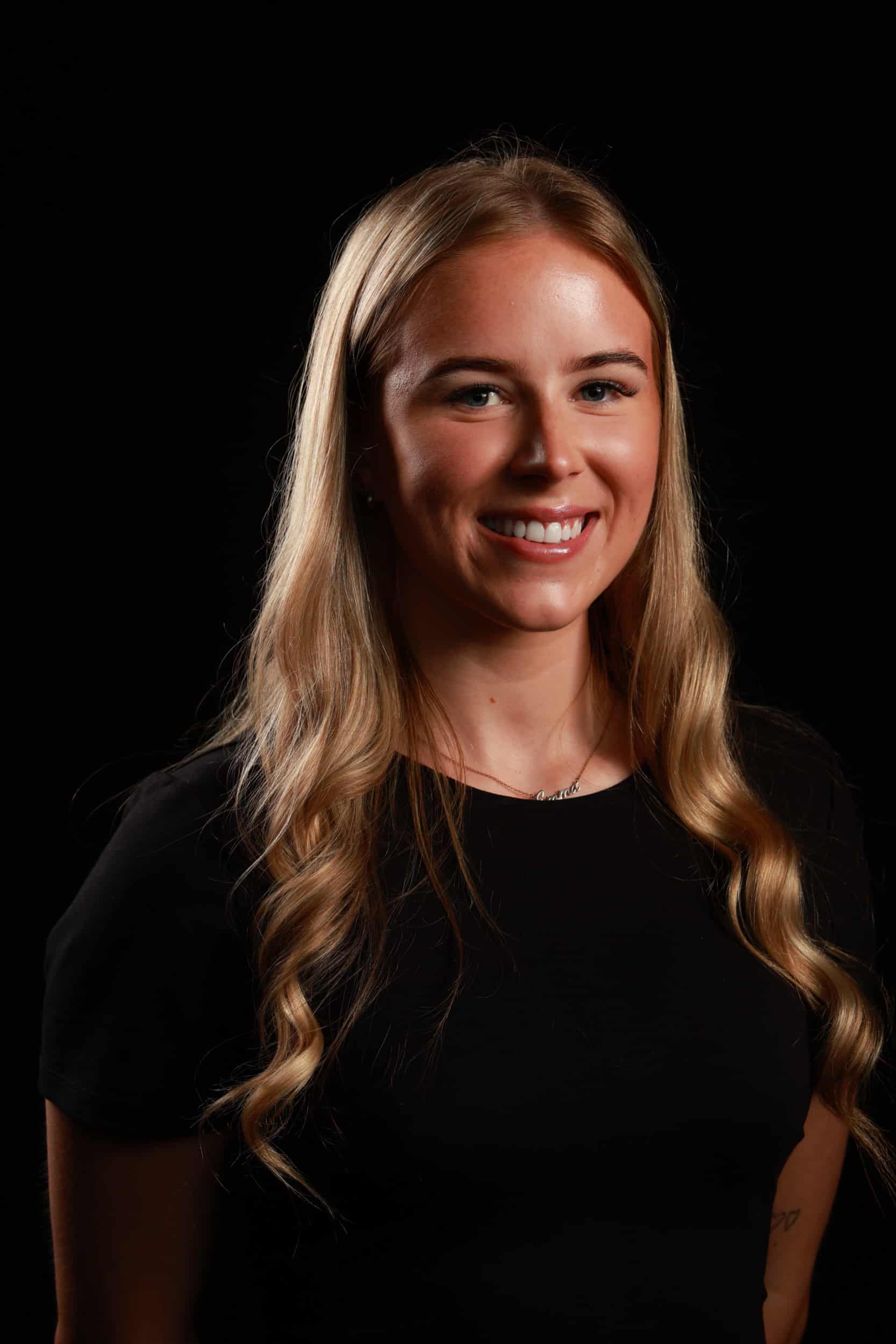 Professional headshot of smiling woman in studio setting with refined lighting.