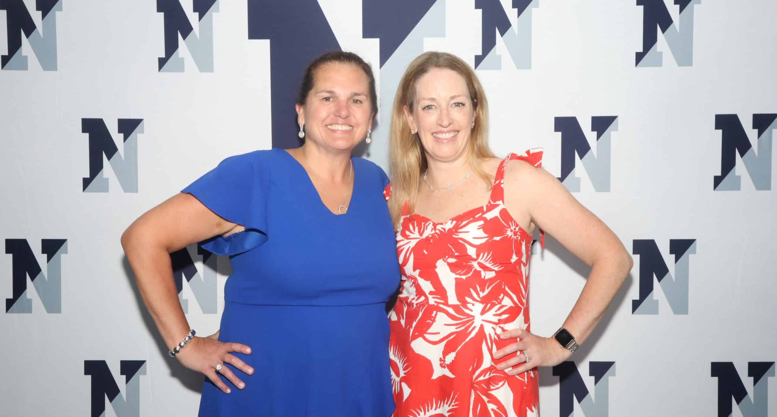 Two women posing in front of a branded backdrop at a Magic Mirror of New England photo booth experience.