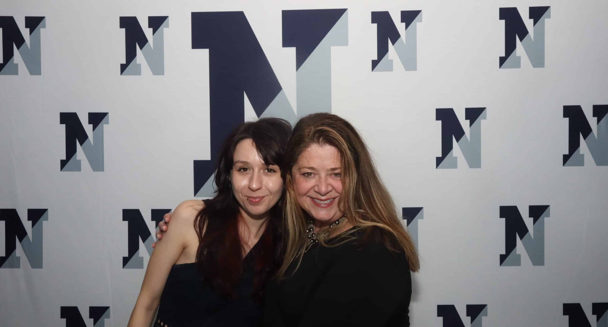 Two women posing in front of a branded backdrop at a Magic Mirror of New England photo booth.