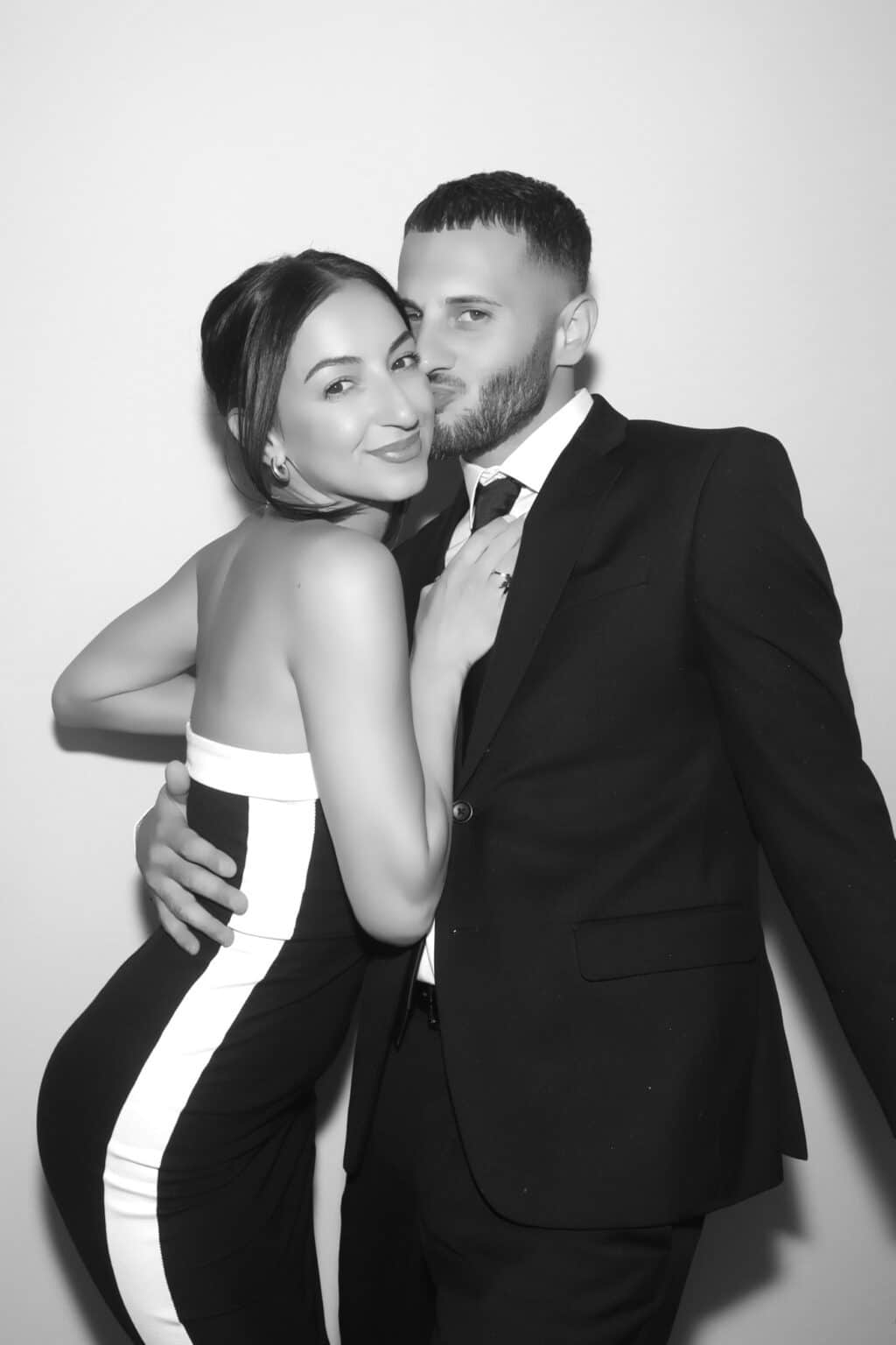 Couple in formal wedding attire embracing for a black and white GLAM photo booth portrait at a wedding in Meredith, NH