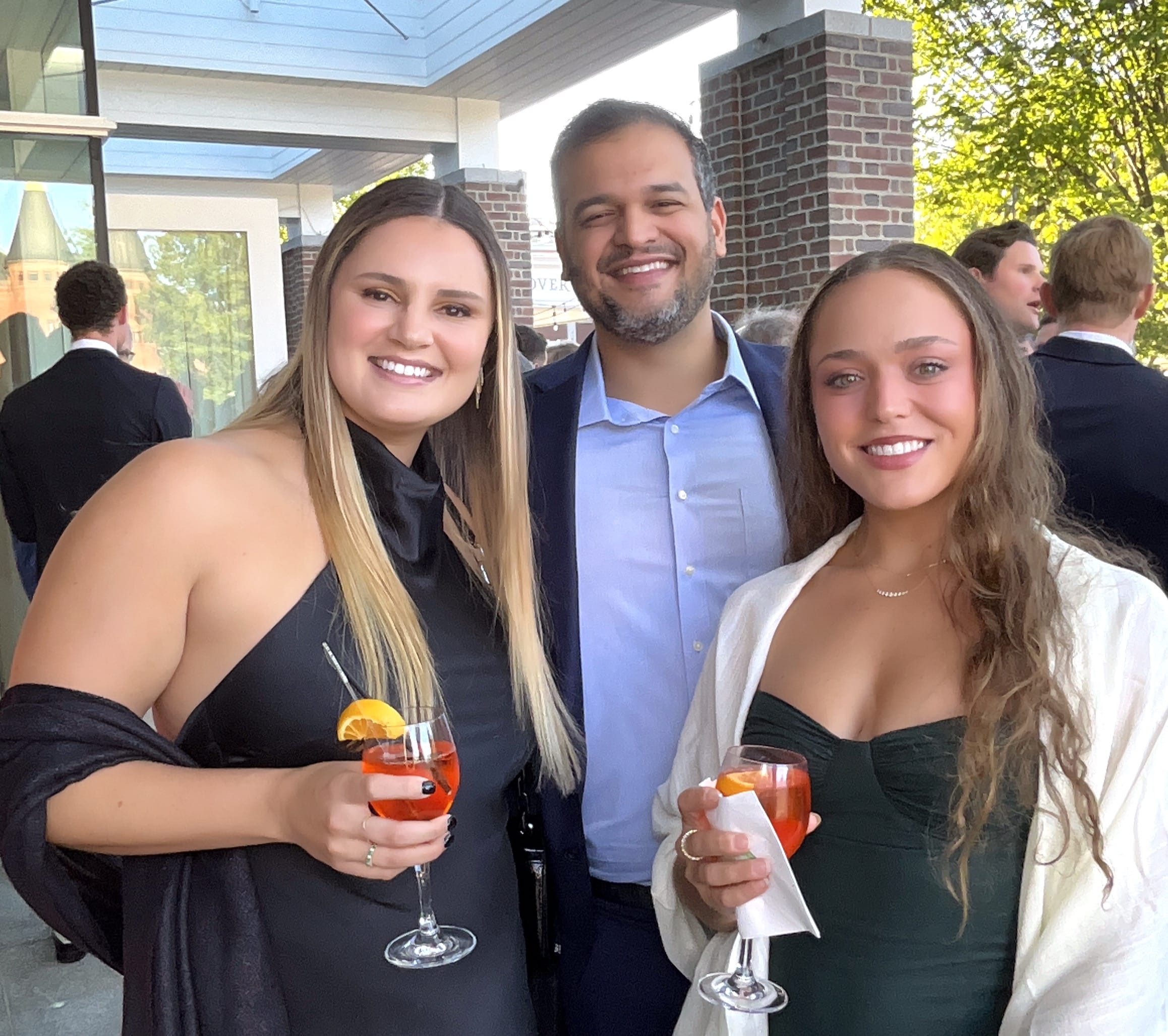 Guests holding spritz cocktails and smiling for a roaming photographer at a wedding cocktail hour in Hanover, NH