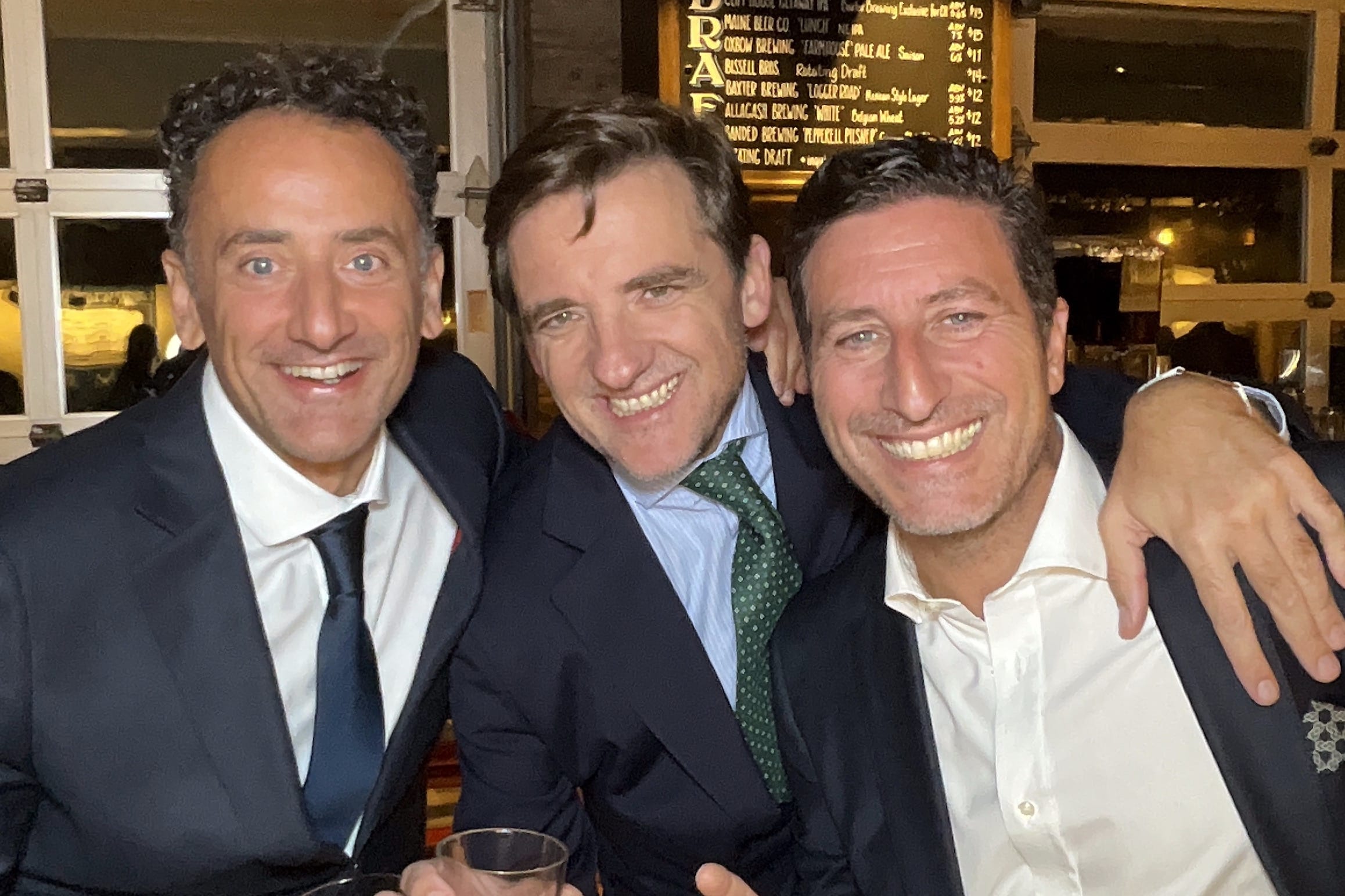 Three guests smiling together at a Maine cocktail hour reception photographed by a roaming photo booth