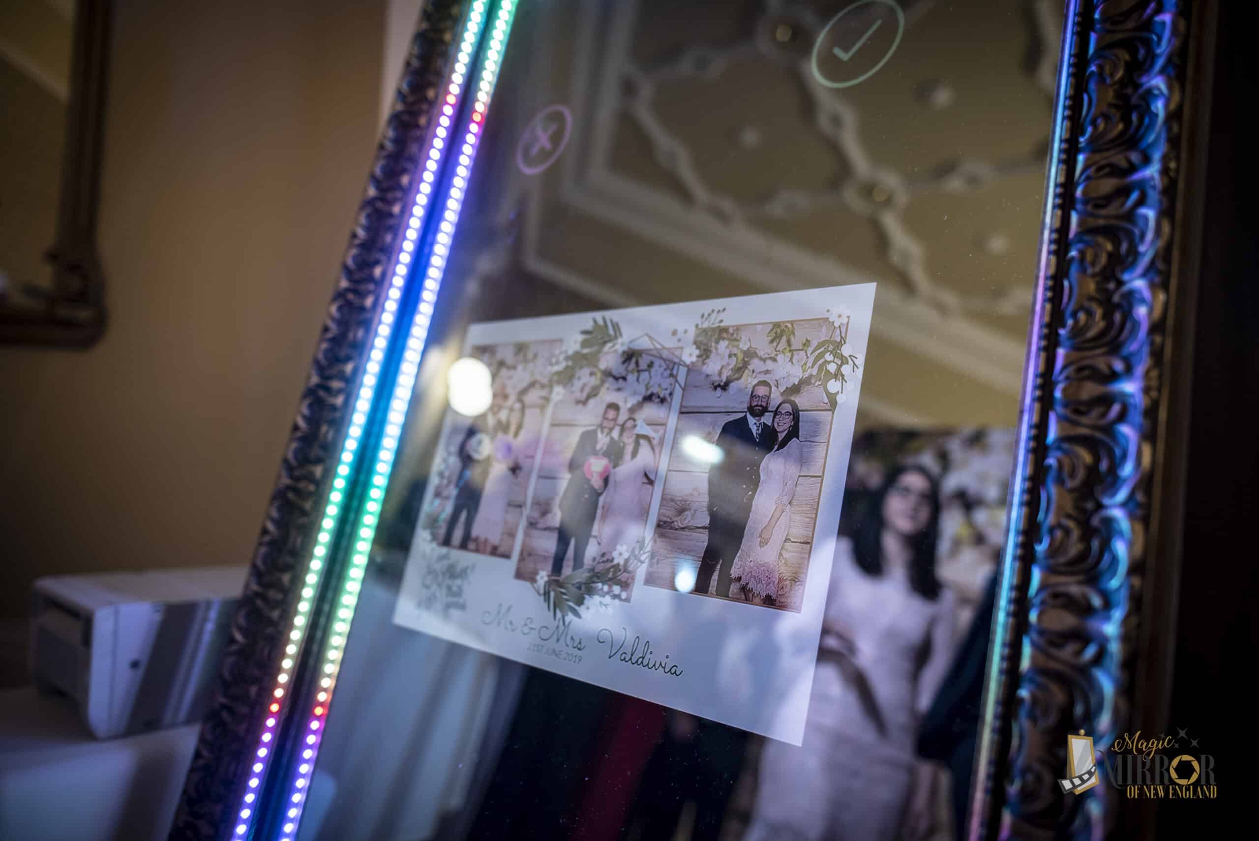 Magic Mirror photo booth with color-changing LED frame displaying a printed photo strip from the event