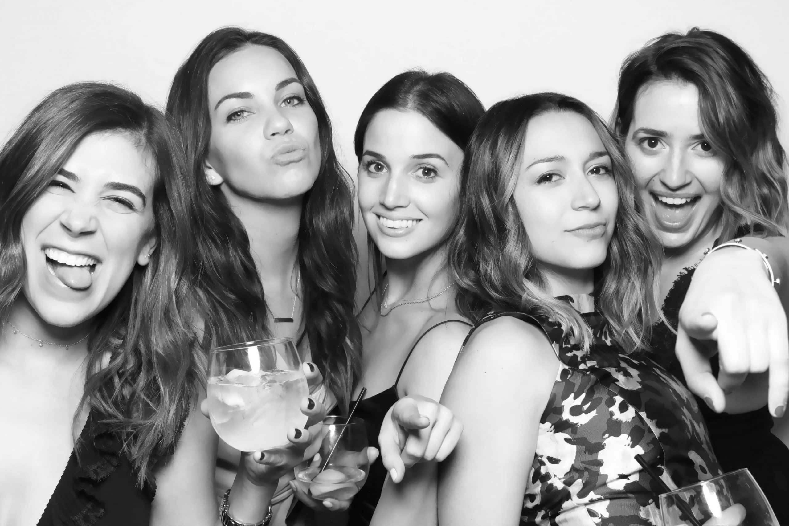 Five friends laughing and pointing at the camera in a black and white GLAM photo booth portrait at an event in New England