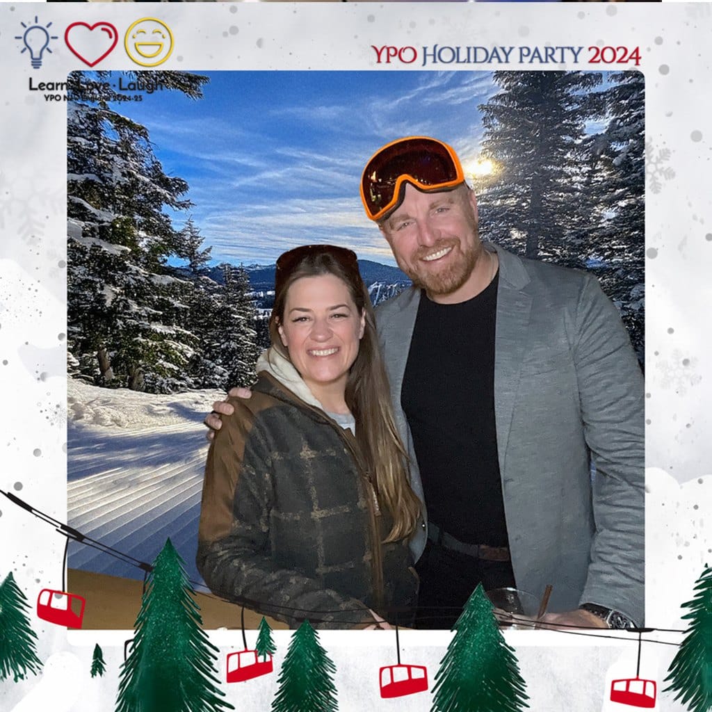 A couple posing in front of a snowy mountain scene with a custom holiday photo template overlay of ski gondolas, pine trees and event branding