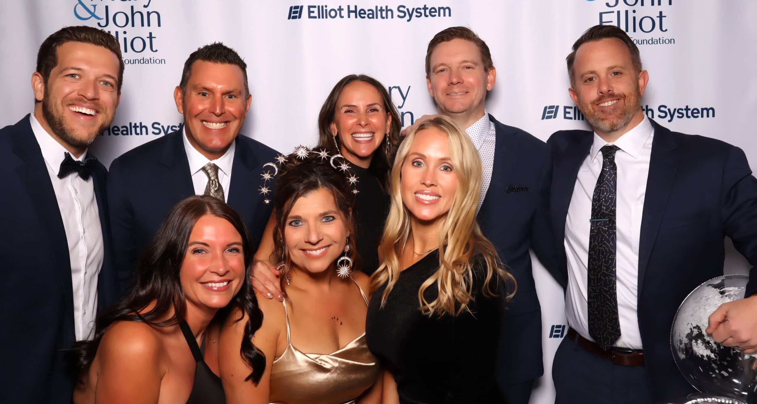 Group of guests in tuxedos and formal dresses at a charity gala photo booth in Manchester, NH