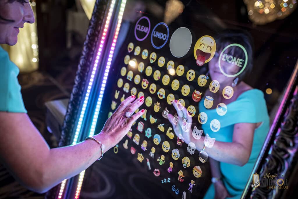 Guests tapping emoji reactions on the Magic Mirror photo booth touch screen with rainbow LED frame