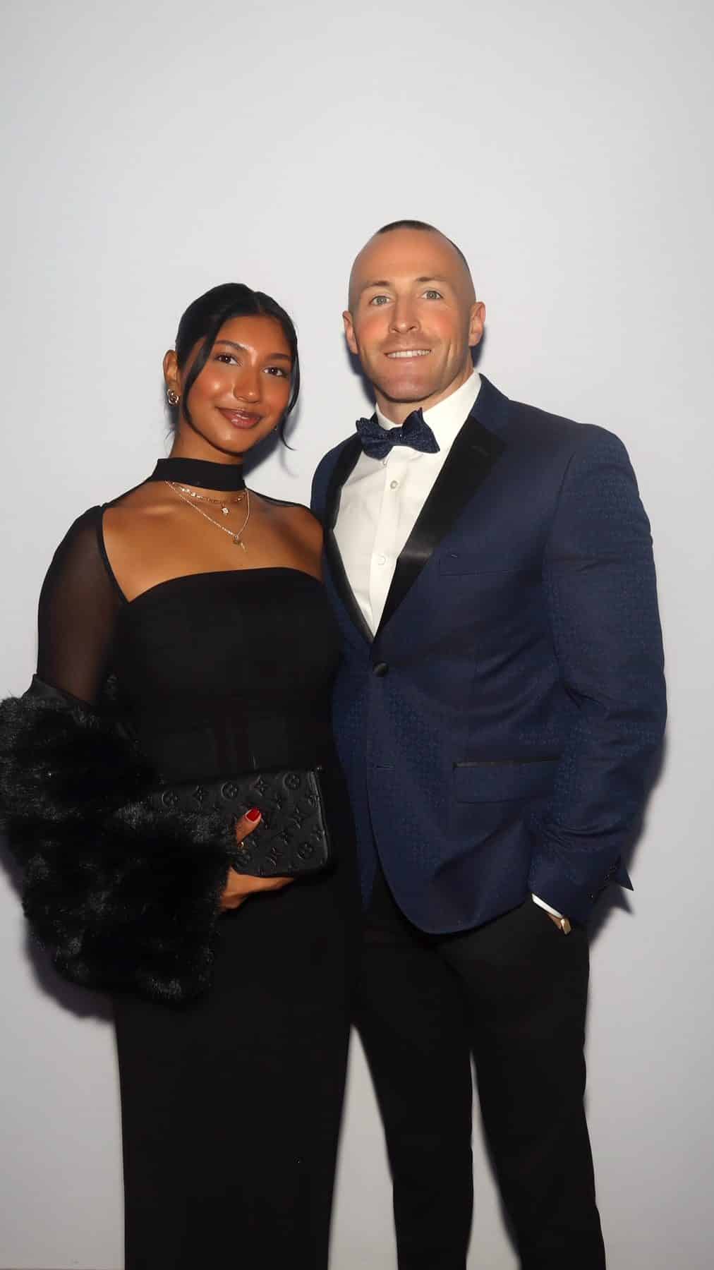 Couple in black tie, she in a sheer black gown and he in a navy tuxedo, in a color GLAM booth photo at a New Hampshire gala