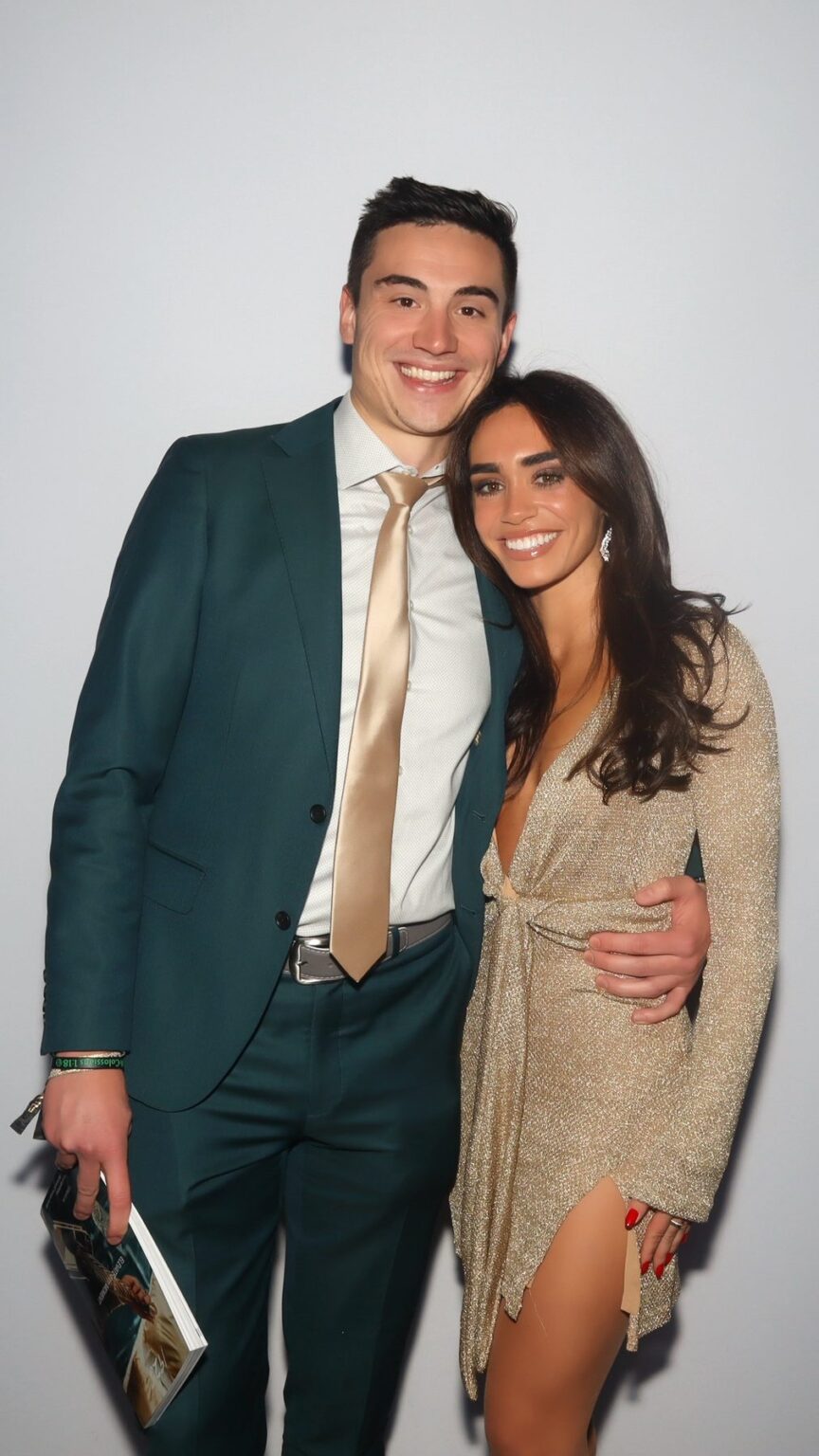 Couple in an emerald suit and a gold dress posing in a color GLAM photo booth portrait at a New England event