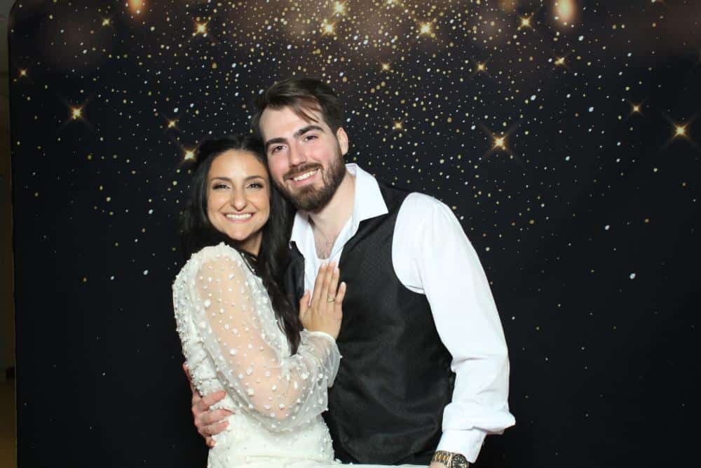 A bride and groom hugging in front of a starry night photo booth backdrop