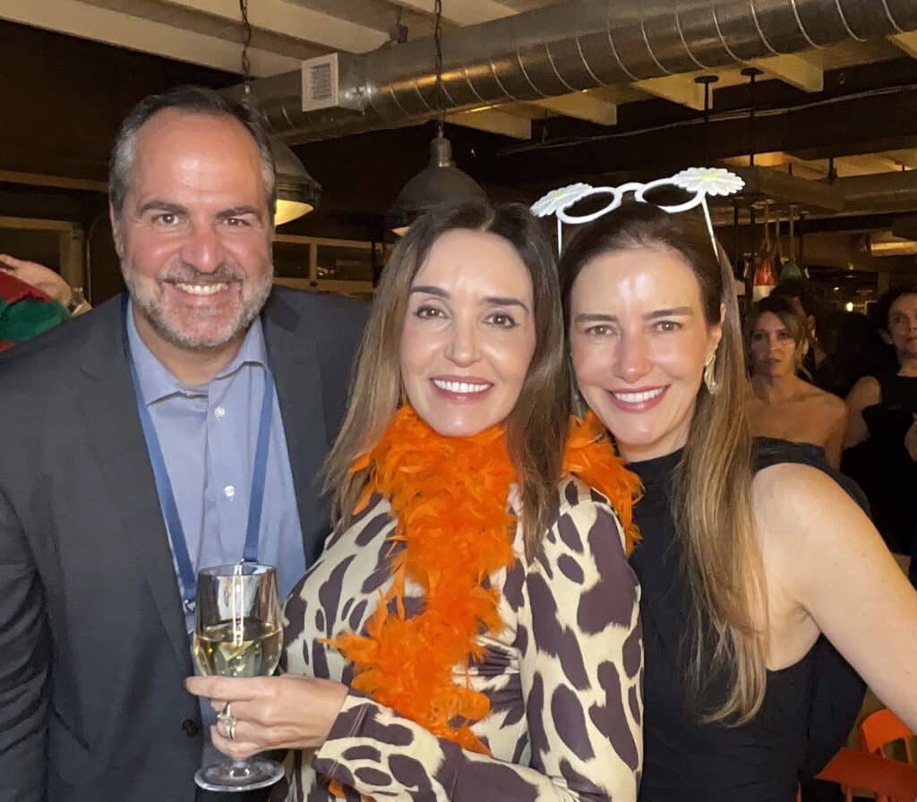 Three guests with a feather boa and holiday props laughing together for the roaming photo booth at a Southern Maine event