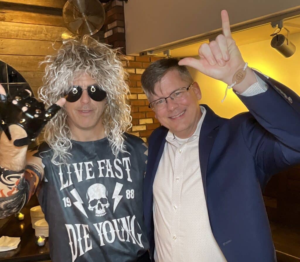 Two guests in rock and roll costumes flashing rock hand signs for the roaming photo booth at a Southern Maine event