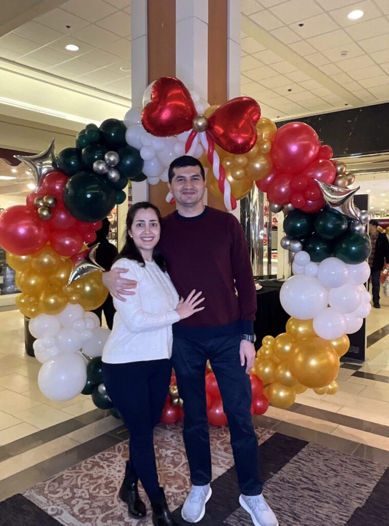 Smiling couple in front of a balloon arch at an event with a drop off photo booth rental